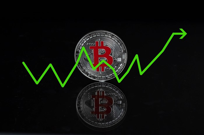 Bitcoin coin with a rising graph on black background