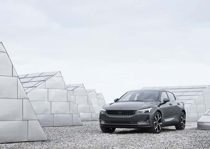 Grey Polestar 2 parked on gravel near modern architecture