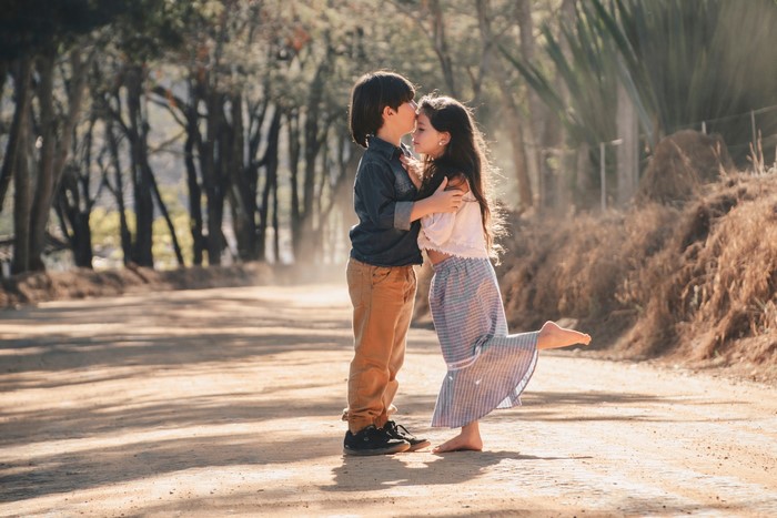 Boy kissing girl on forehead on dirt road