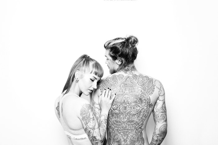 Couple with intricate back tattoos on white background