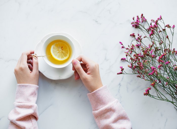 Hands holding a cup of tea with lemon