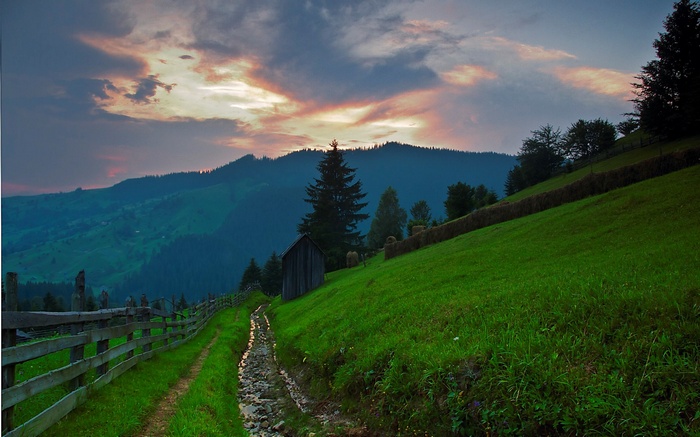 Mountain landscape with a wooden fence and a stream at sunset