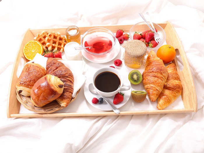 Breakfast tray with coffee, croissants, fruits, and waffles