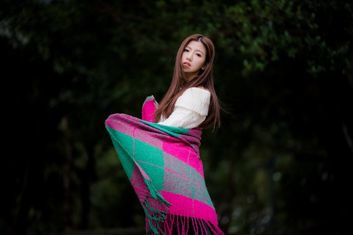 Asian woman with brown hair wrapped in a plaid blanket