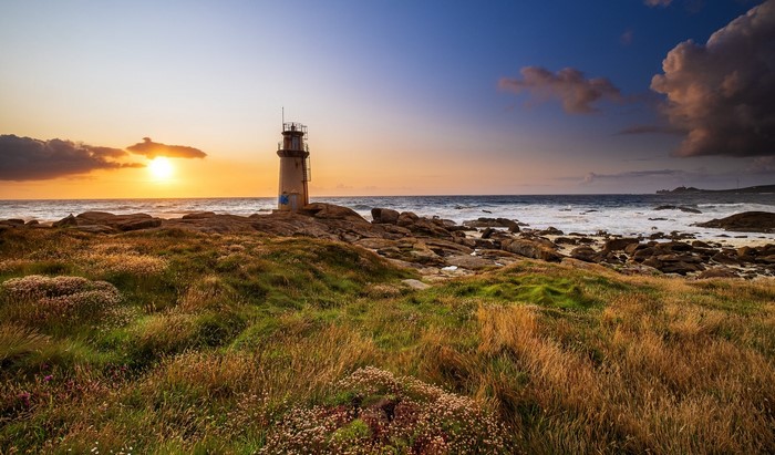 Lighthouse on a rocky coast at sunset in Galicia, Spain