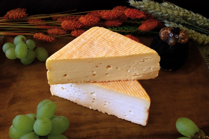 Wedge of cheese with grapes and a sheep figurine