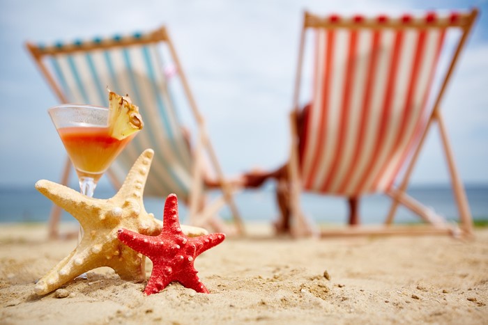 Cocktail and starfish on a sandy beach with lounge chairs