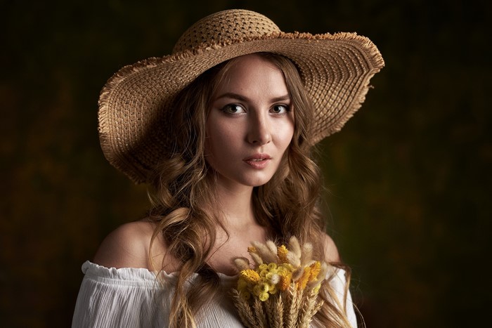 Woman with straw hat holding wheat and flowers
