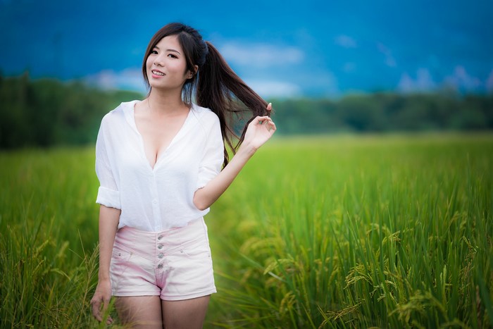 Asian woman in white shirt and shorts in field