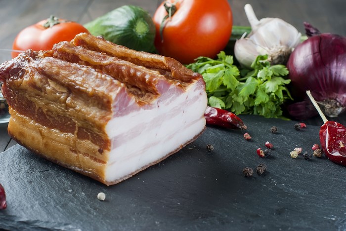 Salo with vegetables and spices on a dark surface