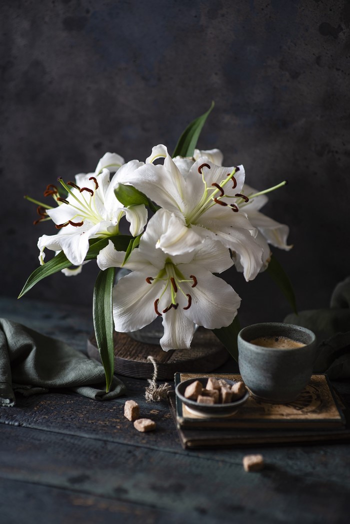 Still life of white lilies with coffee and sugar cubes