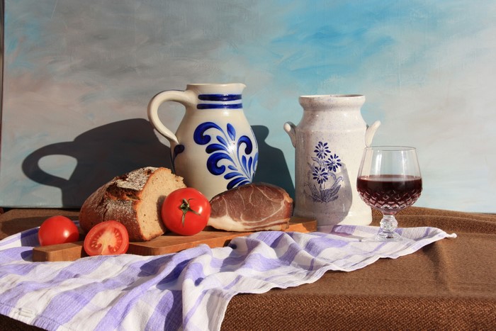 Still-life with bread, tomatoes, ham, jugs, and wine