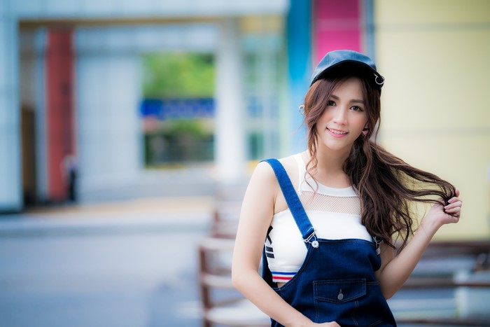 Asian girl in denim overalls and baseball cap