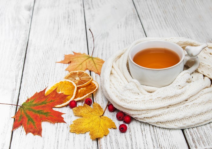 Cup of tea with autumn leaves and scarf
