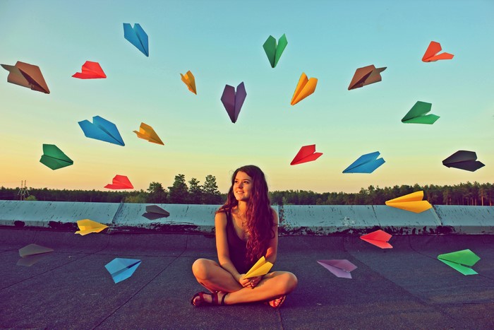 Girl sitting with paper airplanes