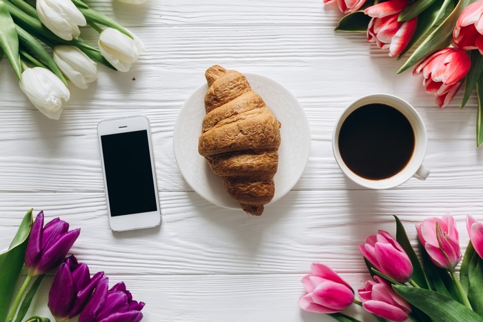 Tulips, Croissant, Coffee, and Smartphone on White Table