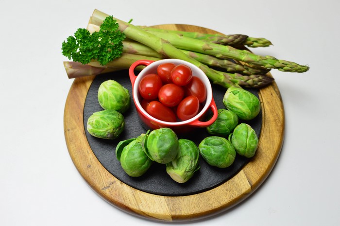 Asparagus, Brussels sprouts, and tomatoes on a cutting board