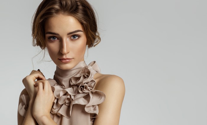 Model with brown hair and blue eyes on gray background
