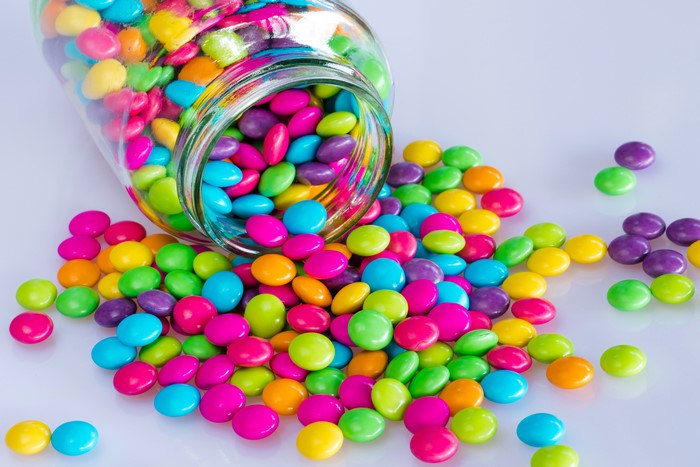 Multicolor candies spilling from a glass jar
