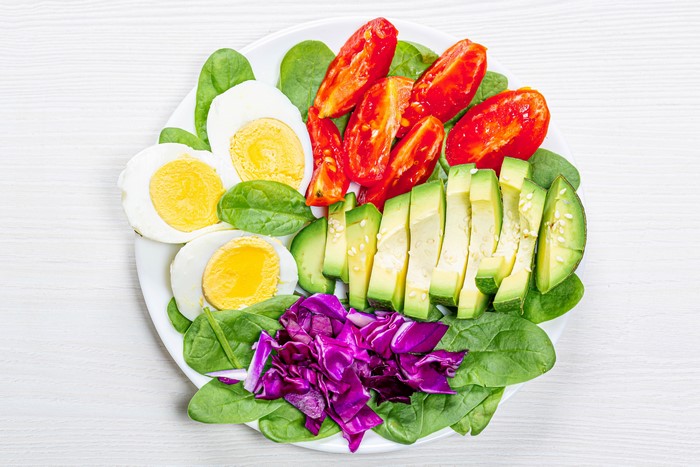 Salad with eggs, avocado, tomatoes, spinach, and cabbage