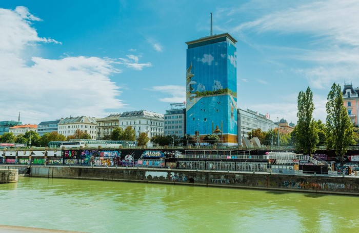 Vienna cityscape with a tall building covered in art and a river