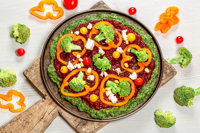 Vegetable pizza with broccoli and bell pepper on cutting board