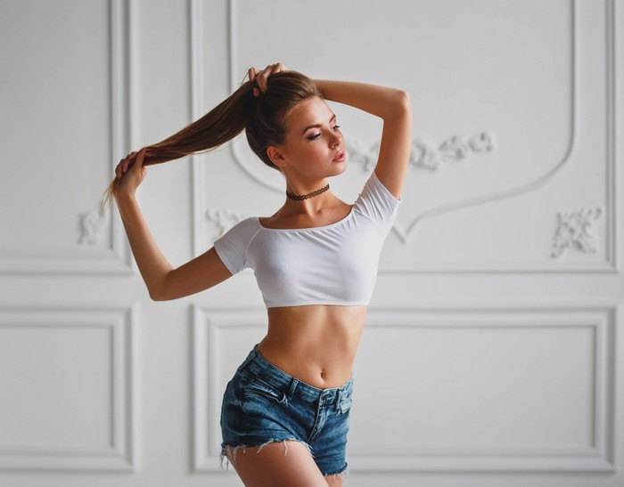 Woman in white crop top and denim shorts posing