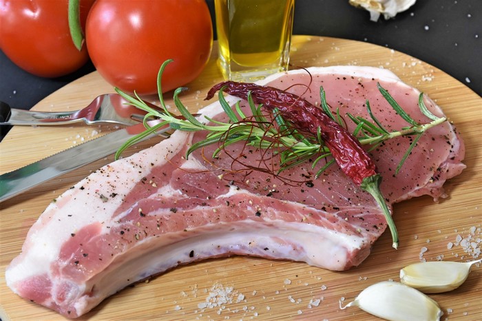 Raw pork chop with spices and tomatoes