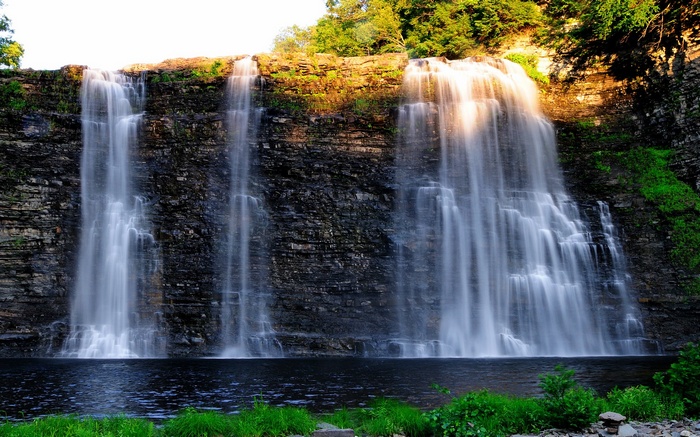 A wide waterfall cascades down a rocky cliff face
