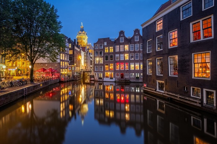 Amsterdam canal at dusk with illuminated houses