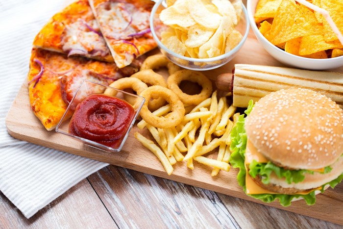 Fast food assortment: pizza, fries, burger, chips, and ketchup