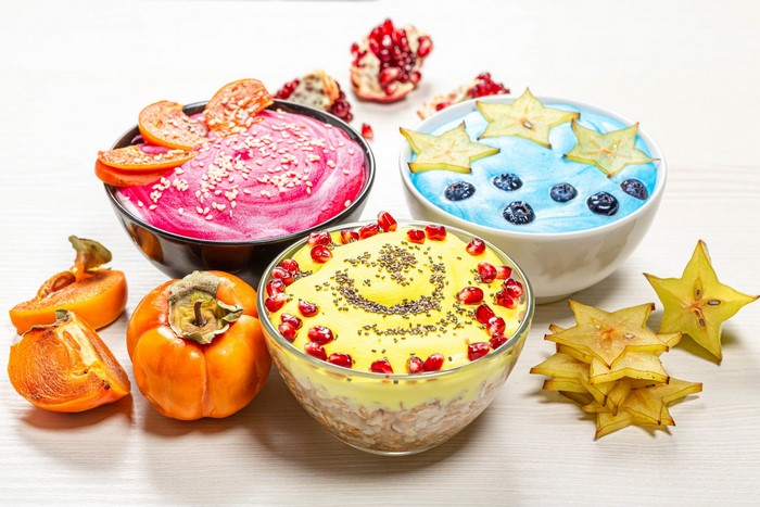 Three bowls of fruit muesli with persimmons and starfruit