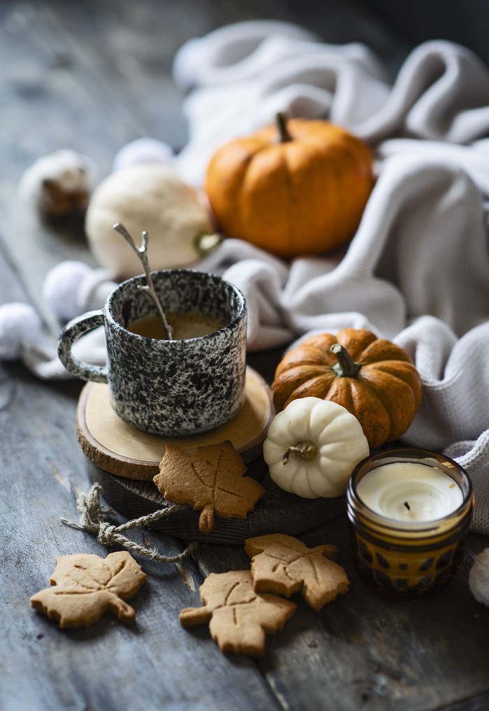 Autumnal still life with coffee, pumpkins, cookies, and candle