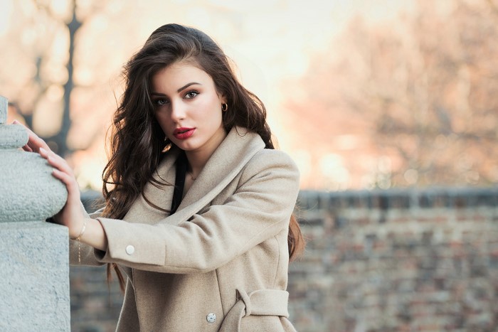 Woman in a beige coat posing outdoors