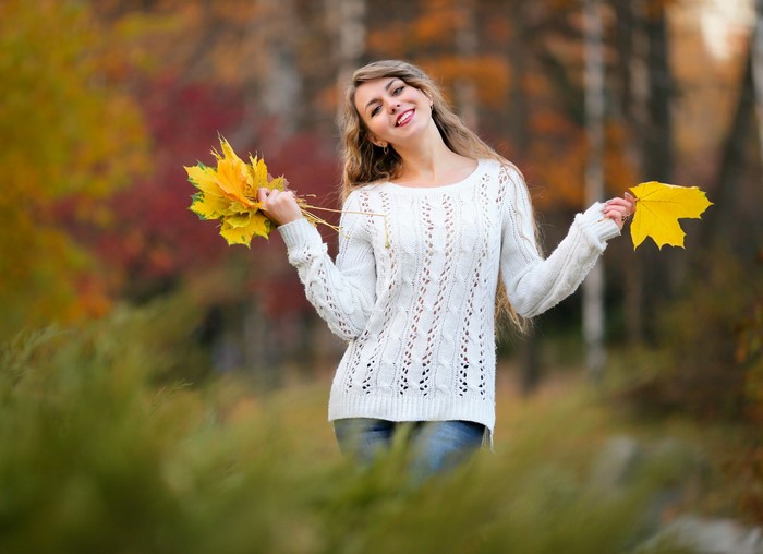 Woman holding autumn leaves in a park