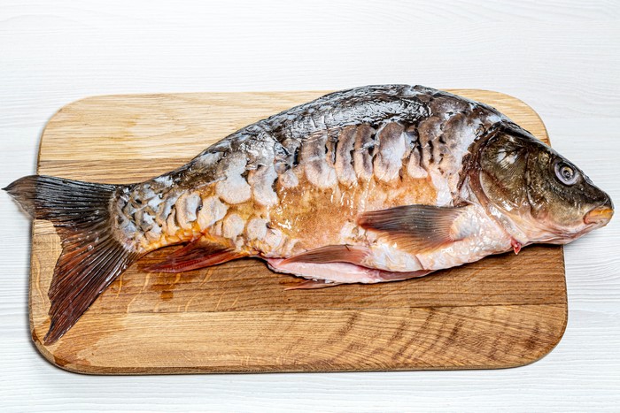 Raw crucian carp on a wooden cutting board