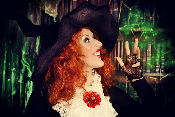 Witch with red hair and a hat casting a spell