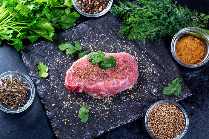 Raw pork chop with spices and herbs