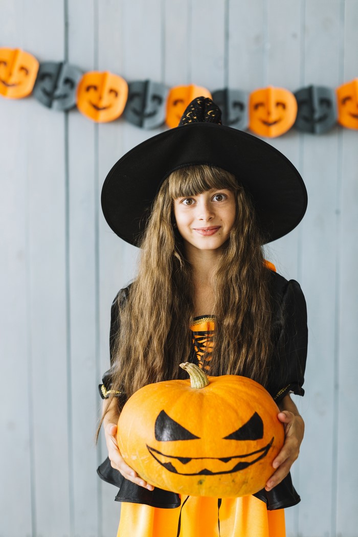 Girl in Witch Costume Holding a Jack-o'-lantern