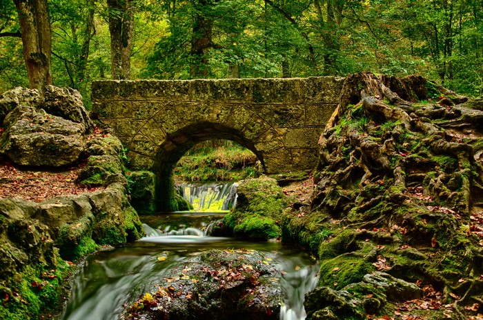 Stone bridge over a stream in an autumn forest