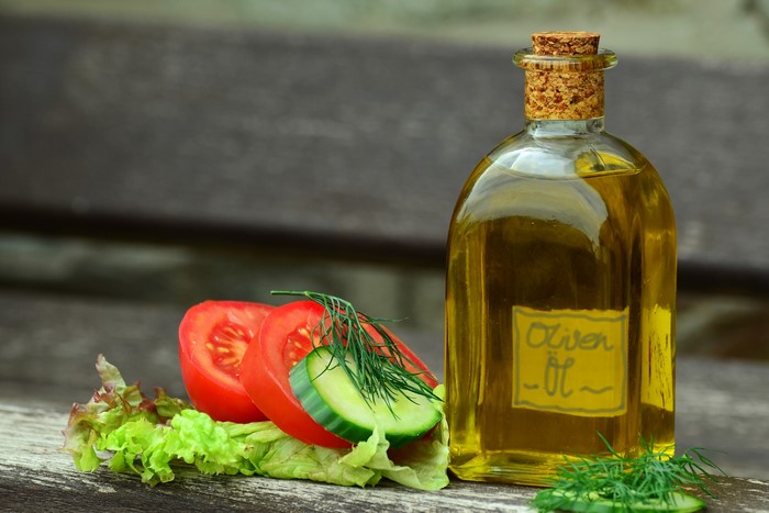 Olive oil bottle with tomatoes, cucumbers, and lettuce