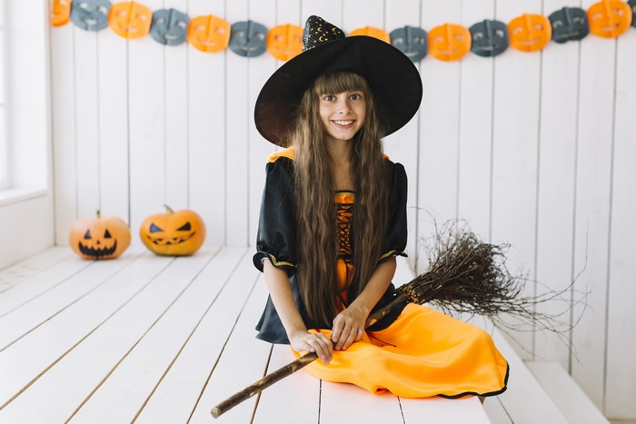 Girl in Witch Costume with Broom and Pumpkins