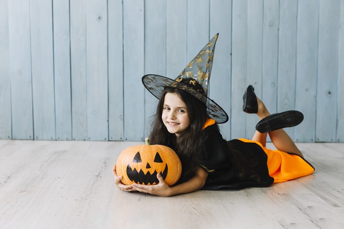 Girl in Witch Costume with Pumpkin