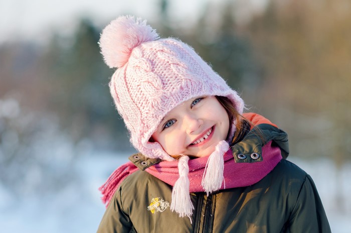Girl in pink winter hat and scarf smiling