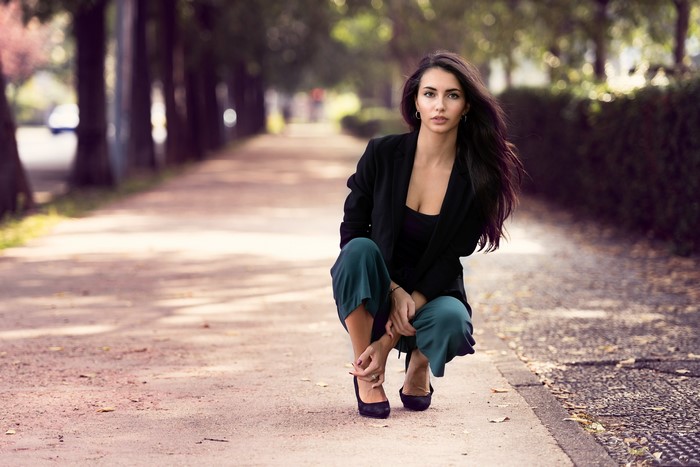 Woman in black blazer and green pants posing outdoors