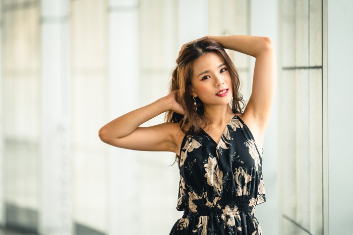 Asian woman in floral dress posing with hands in hair