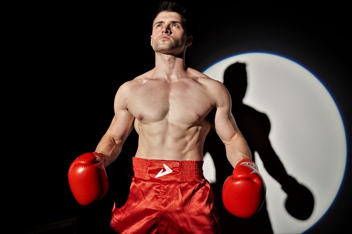 Boxer in red shorts and gloves with shadow