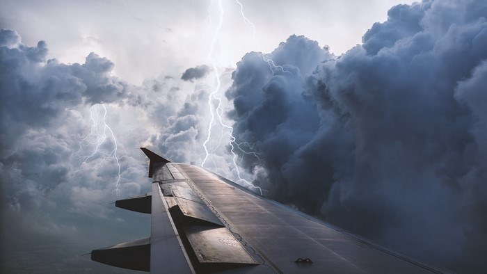 Airplane wing in a thunderstorm with lightning