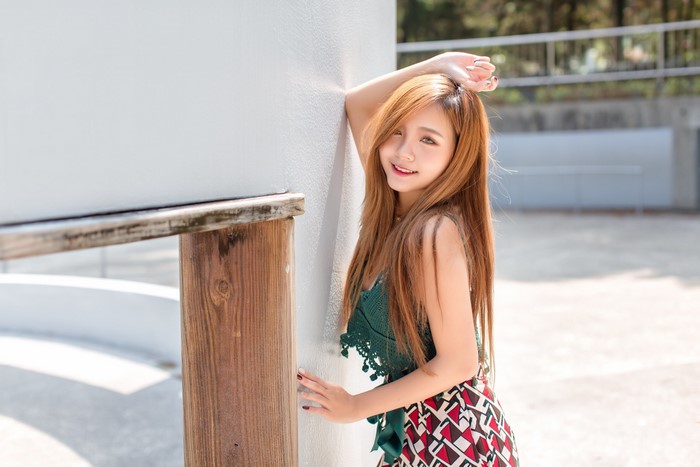 Asian woman posing by a wall