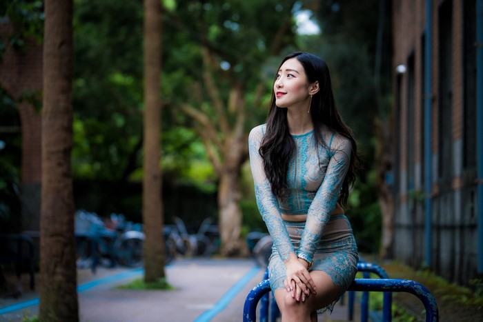 Asian woman in blue lace dress sitting outdoors
